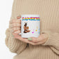 A white ceramic mug with the god pan on it. At the top is the word "pansexual", partially obscurred, in the pan pride colours. To the bottom right, three music notes can be seen, also in the pan pride colours. The cup is being held by a woman in a beige sweater.