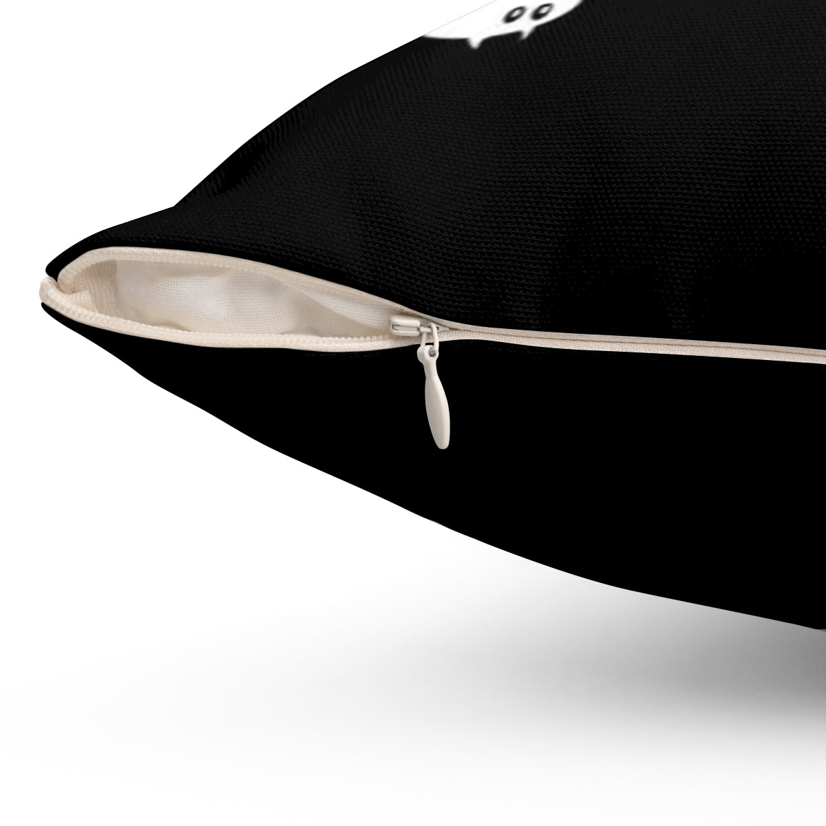 A black throw pillow showing off the zipper that removes the cover. On the upper half, you can see part of a cat print.