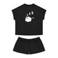 A black pajama shirt and black pajama pants. The shirt has a sleeping cat demon with 3 z's above their head in the middle.