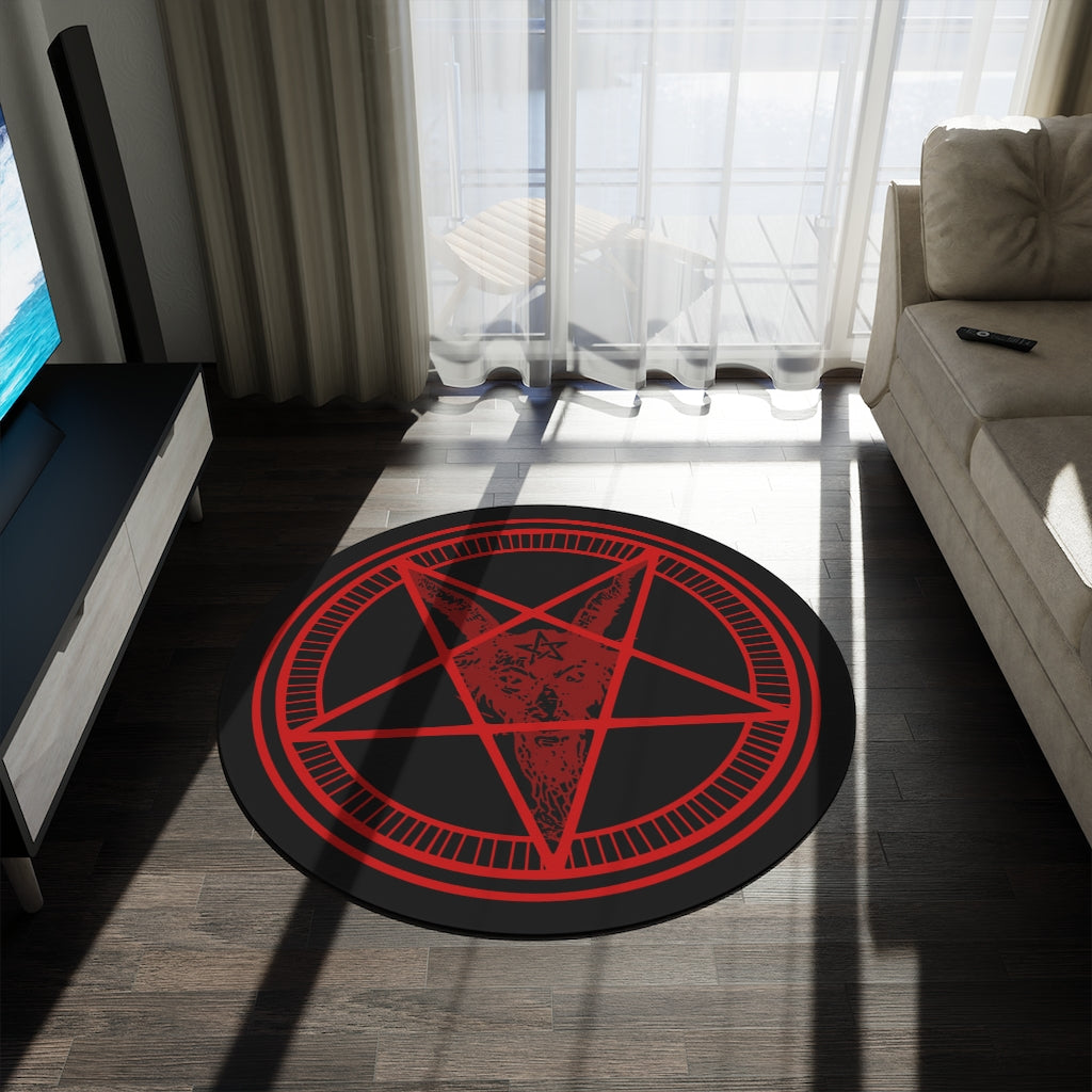 A large baphomet rug sitting in front of a couch in a living room. The rug itself is black with red rings. The inner ring has lines spaced evenly. The center forms a pentacle with a goats head, it's horns at the top points, and its beard flowing down to the bottom. It has a pentagram on its forehead.