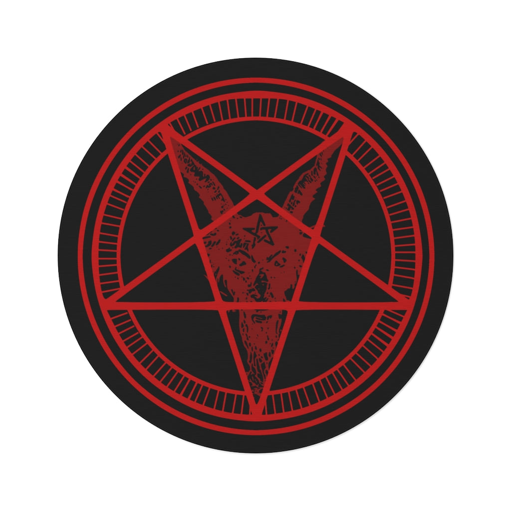 A large baphomet rug sitting on a white background. The rug itself is black with red rings. The inner ring has lines spaced evenly. The center forms a pentacle with a goats head, it's horns at the top points, and its beard flowing down to the bottom. It has a pentagram on its forehead.