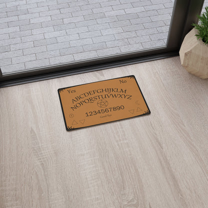 A brown ouija board mat with a black boarder. There's a pentacle in the middle. It's sitting on a wooden floor in front of a glass sliding door.