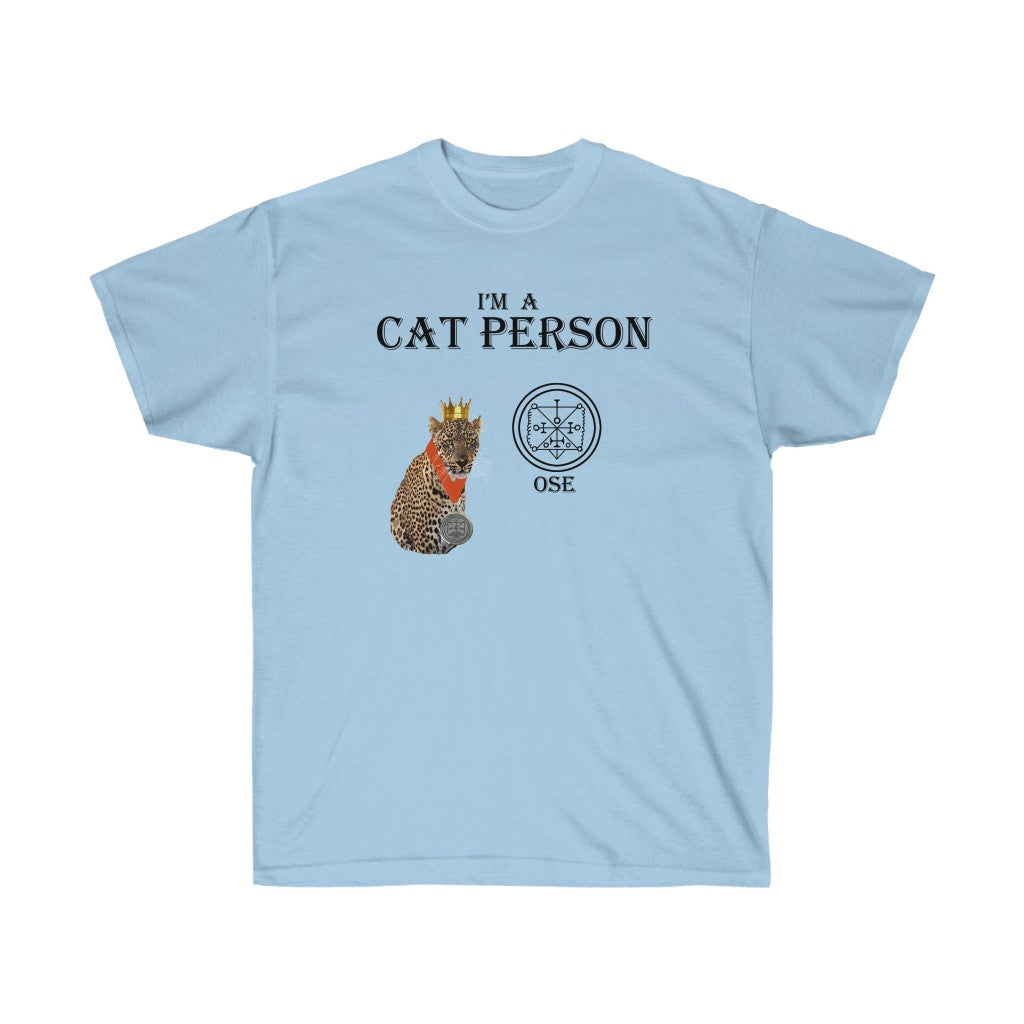 A light blue shirt. It has a leopard based on Ose in the middle. At the top, there is text that reads "I'm a cat person." Below the text is a leopard wearing a golden crown and a medal. Beside the leopard is Ose's Sigil with the name "Ose" below it.