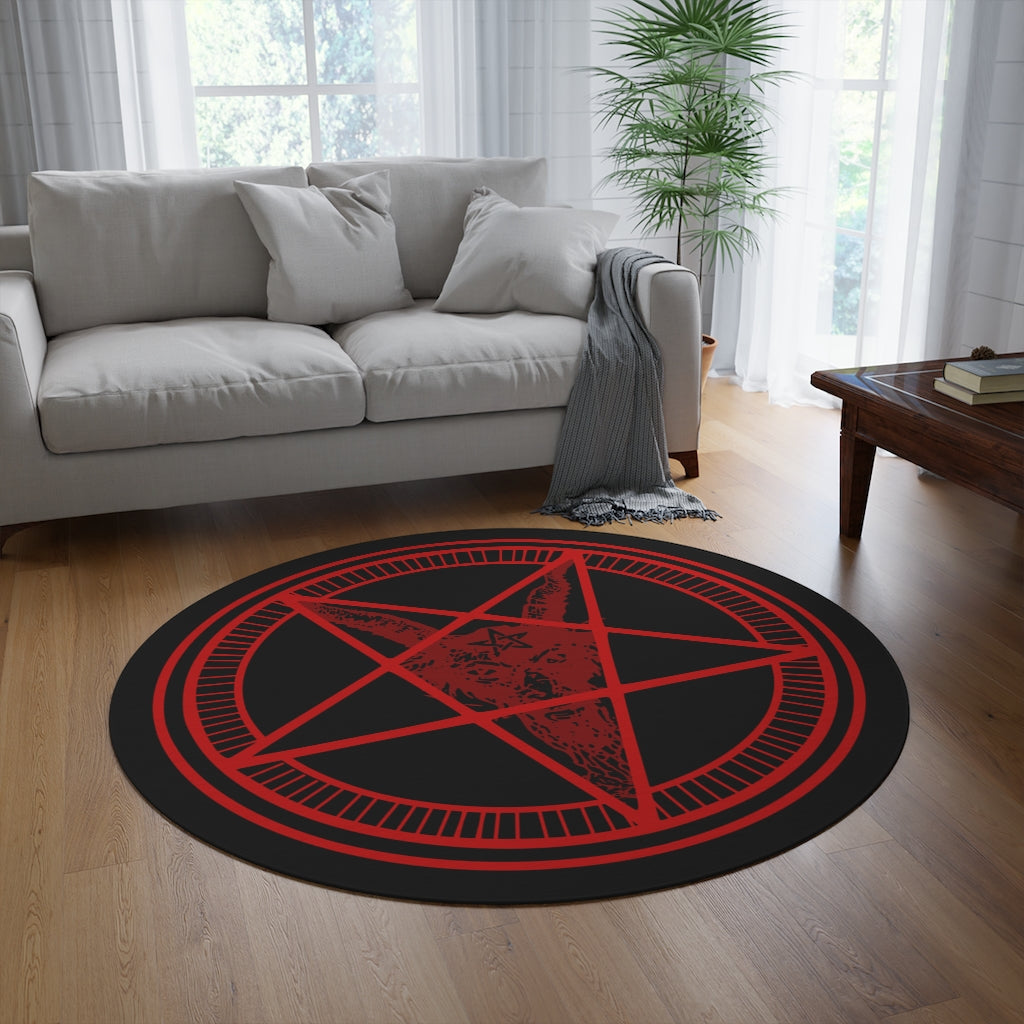 A large baphomet rug sitting in front of a couch in a living room. The rug itself is black with red rings. The inner ring has lines spaced evenly. The center forms a pentacle with a goats head, it's horns at the top points, and its beard flowing down to the bottom. It has a pentagram on its forehead.