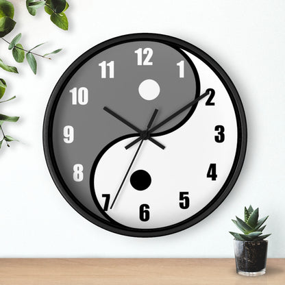 A gray and white yin and yang clock hanging on a wall. To the top right is a hanging vine plant. To the bottom right is a succubus.