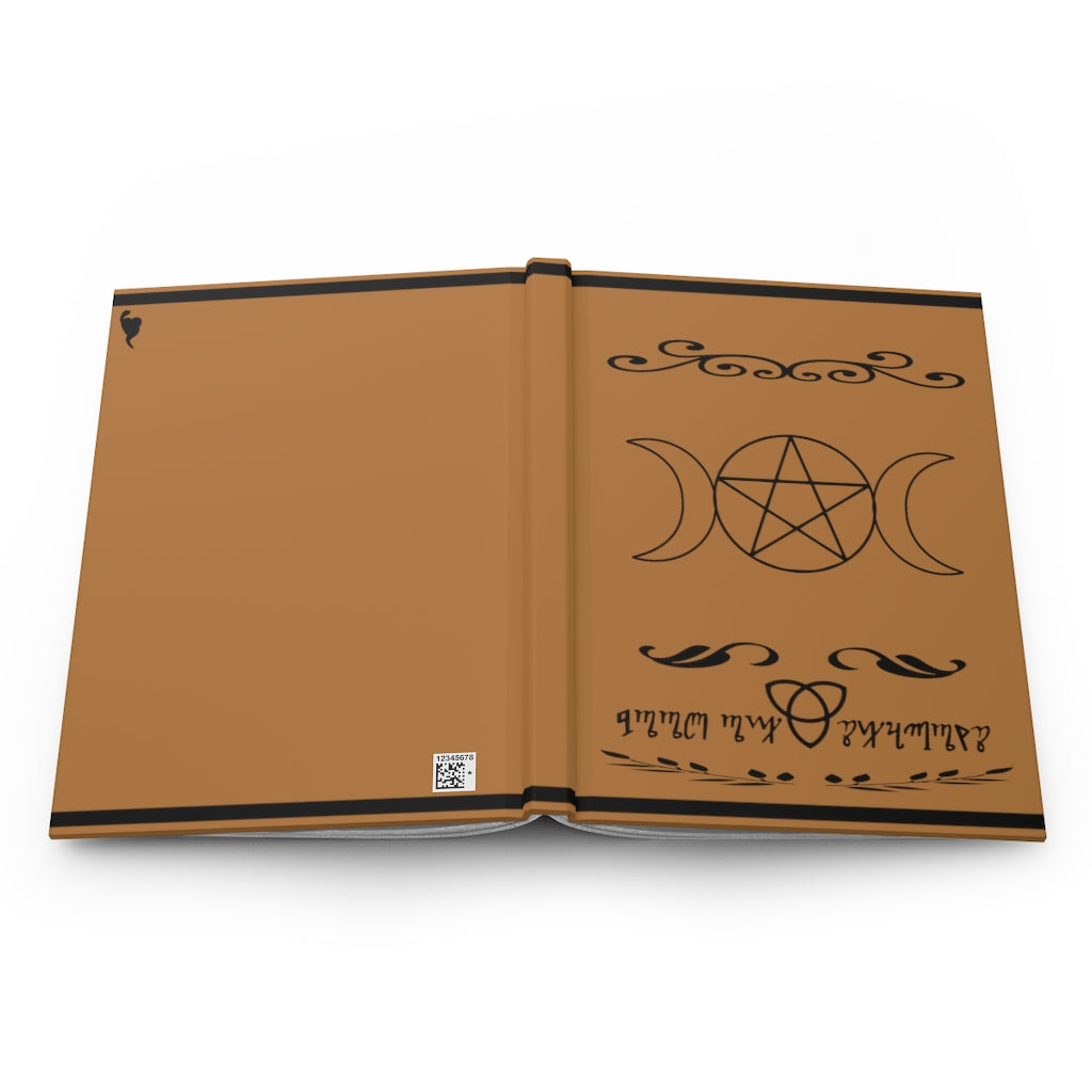 A brown book of shadows laying open flat on a white background. The front showcases a triple moon pentacle in the middle. The bottom shows a celtic knot with the words "Book of shadows" written in theban script. On the back, the Serpent's Heart Shop Logo is showcased on the right left of the book.